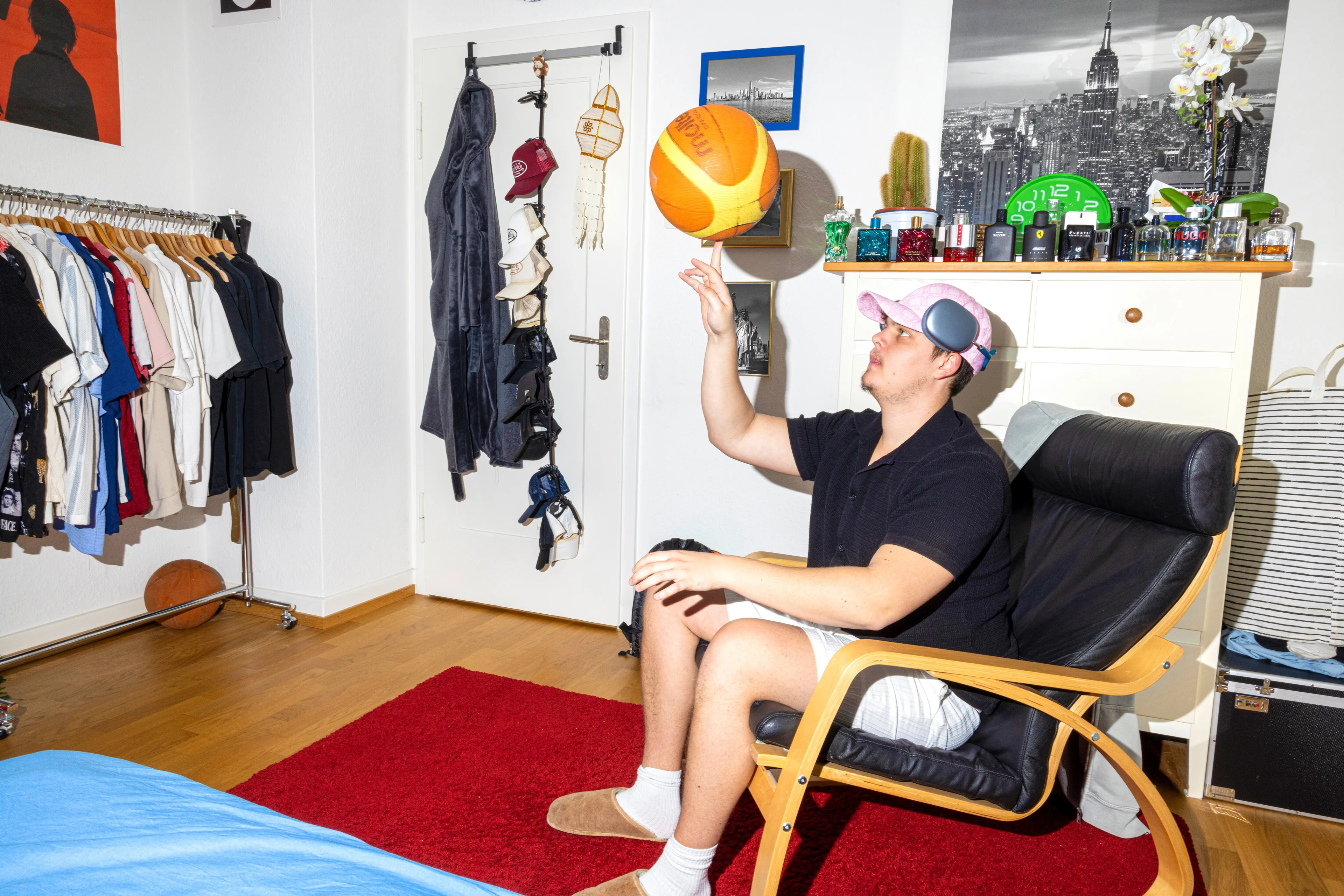 Ein junger Mann sitzt auf einen Stuhl und balanciert einen Ball auf seinem Finger.